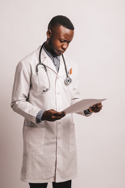 Imagen en primer plano del joven médico afroamericano de pie en uniforme blanco contra blanco