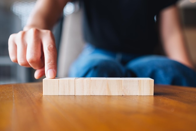 Imagen de primer plano de una mano eligiendo y recogiendo siete piezas de bloque de cubo de madera en blanco