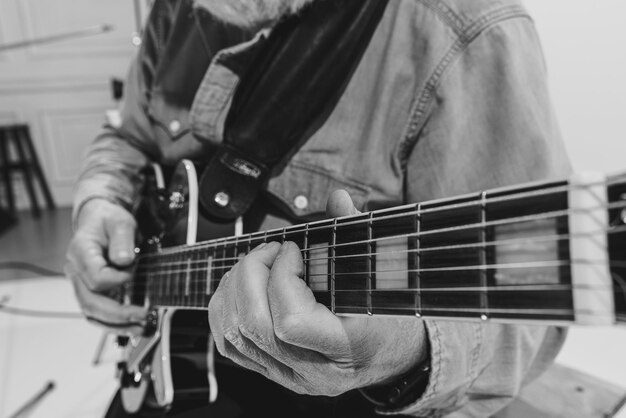 Imagen de primer plano de la mano masculina tocando la guitarra Fotografía en blanco y negro Cultura musical retro