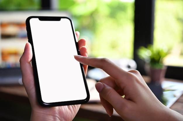 Foto imagen de primer plano de manos femeninas con smartphone con pantalla en blanco en blanco