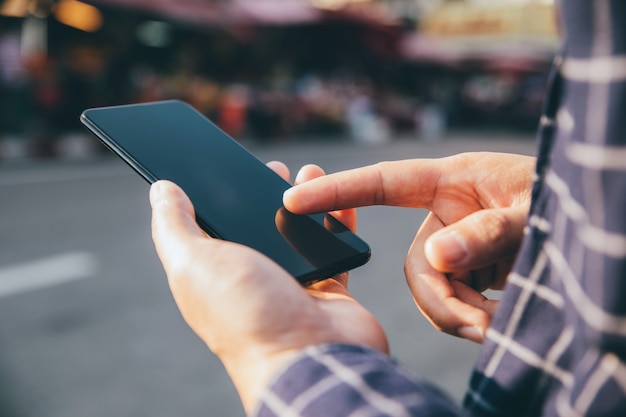 Imagen de primer plano de manos masculinas con smartphone en la calle comercial de la ciudad, búsqueda o concepto de redes sociales,