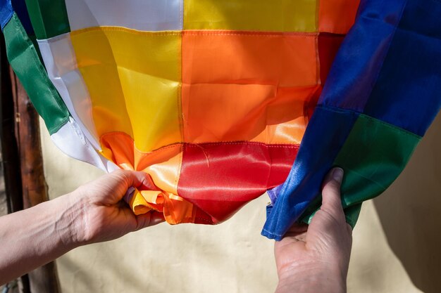 Foto imagen en primer plano de las manos de una mujer agarrando una bandera de seda wiphala