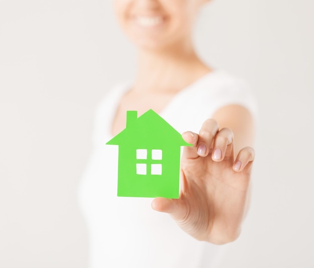 Imagen en primer plano de manos de mujer sosteniendo la casa verde