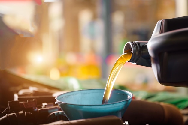 Imagen en primer plano de un mecánico cambiando aceite nuevo a un automóvil En un centro de servicio o tienda de cambio de aceite de automóvil Almacén de automóviles para la industria automotriz