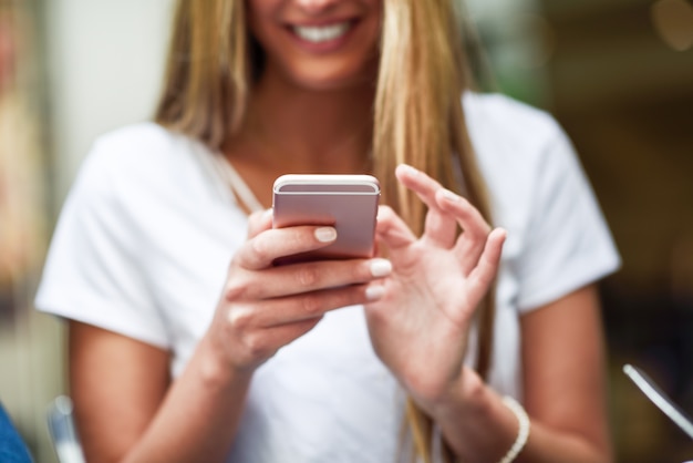 Imagen de primer plano de mensajes de texto chica rubia joven con smartphone