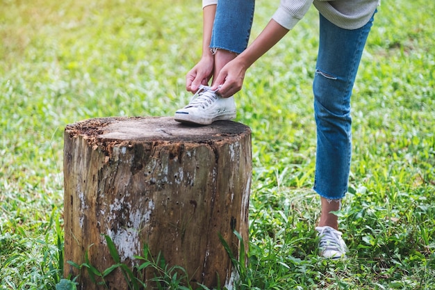 Imagen de primer plano de una mujer atándose los cordones de los zapatos en el parque