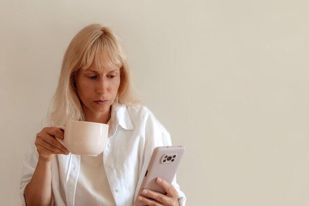 Imagen de primer plano de una mujer bonita sentada en el acogedor interior de la casa y usando un moderno dispositivo de teléfono inteligente manos femeninas escribiendo mensajes de texto a través del concepto de redes sociales de teléfonos celulares