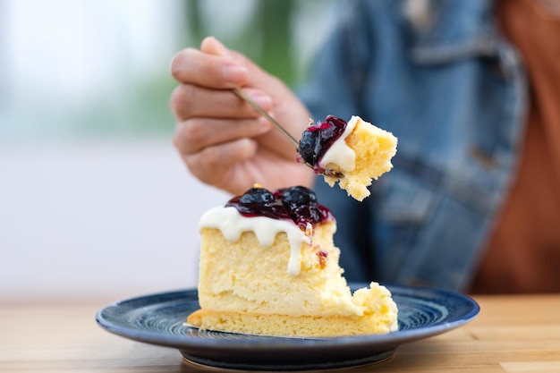 Imagen de primer plano de una mujer comiendo tarta de queso de arándanos con una cuchara