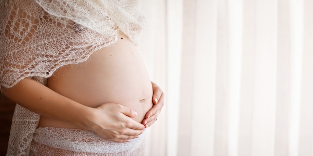 Imagen de primer plano de mujer embarazada tocando su vientre con las manos. Copia espacio