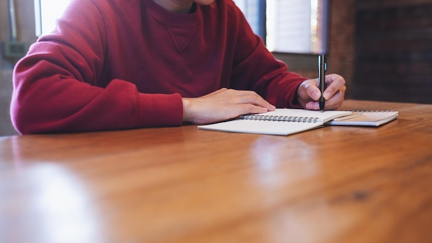 Imagen en primer plano de una mujer escribiendo en un cuaderno en la mesa