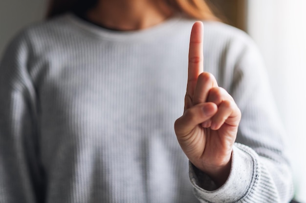 Imagen de primer plano de una mujer haciendo y mostrando el signo de la mano número uno