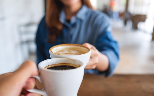 Imagen de primer plano de una mujer y un hombre tintineando tazas de café juntos en el café