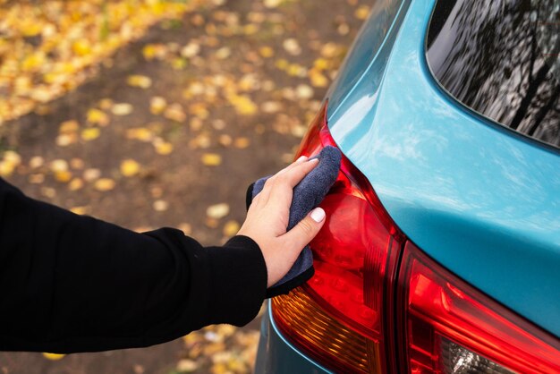 Foto imagen de primer plano de una mujer joven que limpia su coche con un paño de microfibra después de lavarlo limpiando las ventanas de los automóviles transporte concepto de cuidado de autoservicio protección de pintura