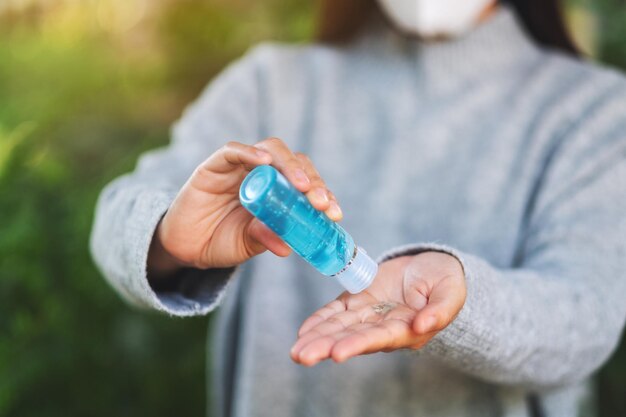 Imagen de primer plano de una mujer con mascarilla protectora y aplicando gel de alcohol para limpiar las manos para el concepto de virus Healthcare y Covid-19 o 2020