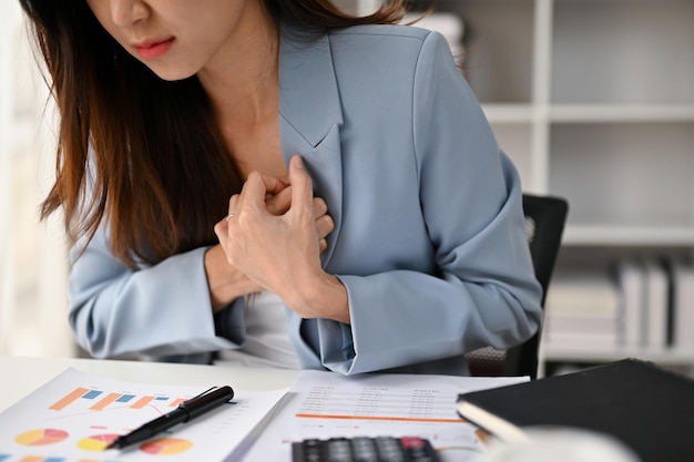 Imagen de primer plano de una mujer de negocios asiática enferma que siente dolor en el pecho ataque al corazón durante el trabajo