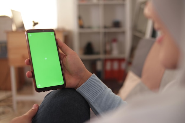 Imagen en primer plano de una mujer que sostiene un teléfono con una plantilla de pantalla verde