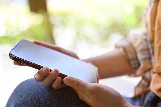 Imagen de primer plano Una mujer se sienta en el parque y usa su teléfono inteligente moderno