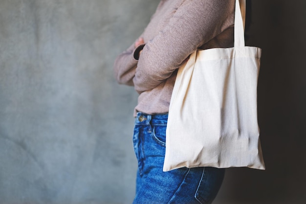 Imagen de primer plano de una mujer sosteniendo y llevando una bolsa de tela blanca para un concepto reutilizable y ambiental