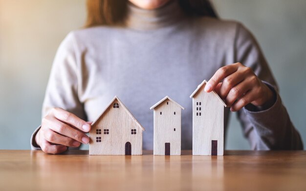 Imagen de primer plano de una mujer sosteniendo modelos de casas de madera sobre la mesa