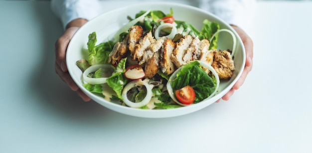 Imagen de primer plano de una mujer sosteniendo un plato de ensalada de pollo