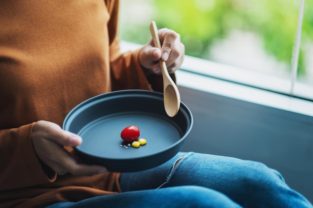 Imagen de primer plano de una mujer sosteniendo un plato de una pequeña cantidad de comida por concepto de dieta