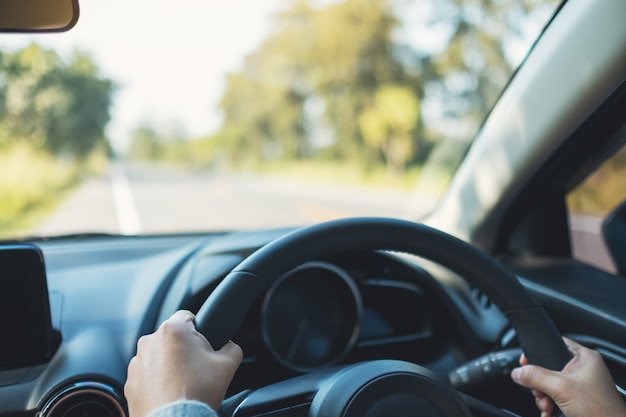 Foto imagen de primer plano de una mujer sosteniendo el volante mientras conduce un automóvil en la carretera