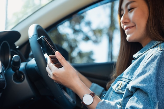 Imagen de primer plano de una mujer con teléfono móvil mientras conduce un coche