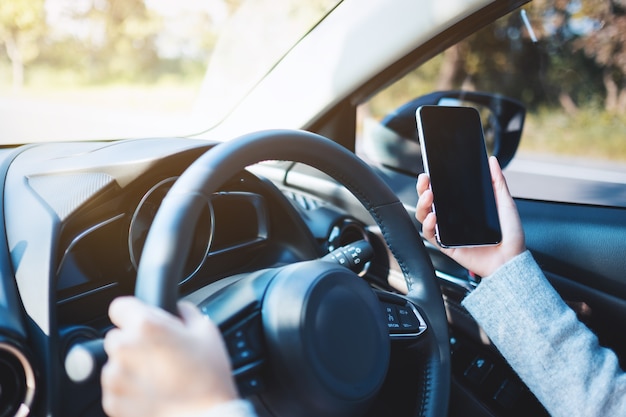 Imagen de primer plano de una mujer con teléfono móvil mientras conduce un coche