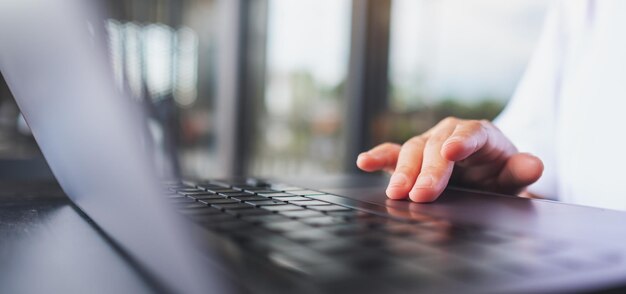 Imagen de primer plano de una mujer trabajando y tocando en el panel táctil de la computadora portátil sobre la mesa