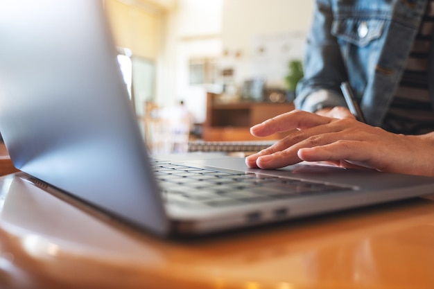 Foto imagen en primer plano de una mujer trabajando y tocando el touchpad de una computadora portátil en la mesa