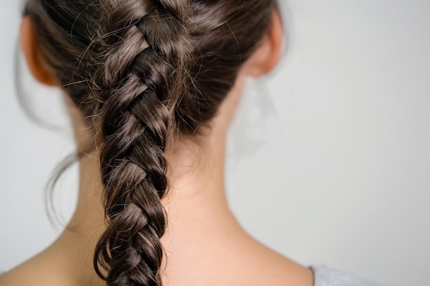 Imagen en primer plano de una mujer con una trenza detallada de cola de pez contra un fondo neutral