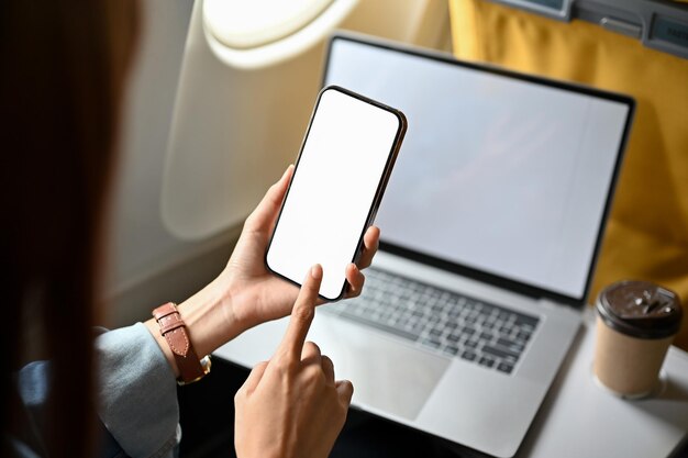 Imagen de primer plano Mujer viajera usando un teléfono inteligente y una computadora portátil en el avión