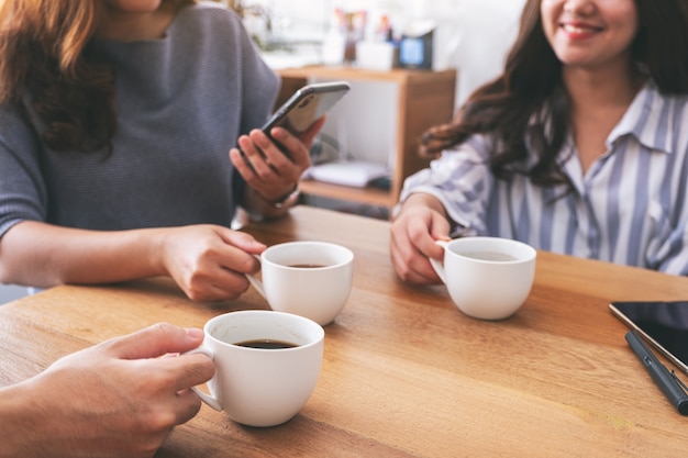 Imagen de primer plano de personas que usan teléfonos móviles y beben café juntos