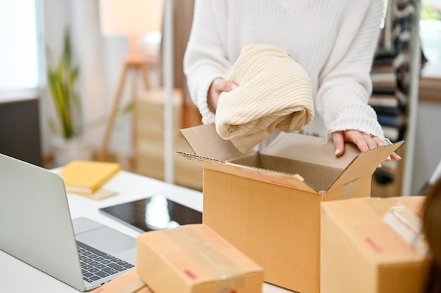 Imagen de primer plano de una vendedora de ropa de moda femenina empacando un producto de envío