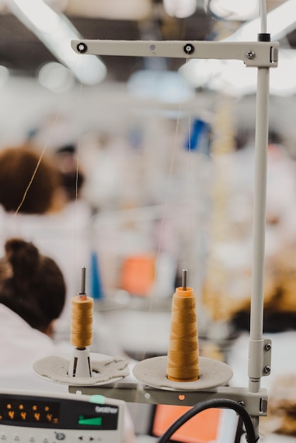 Imagen de primer plano vertical de hilos de coser en una máquina de cosir en una fábrica textil