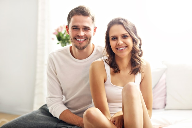 Imagen que muestra la feliz pareja sentada en la cama en ropa de dormir