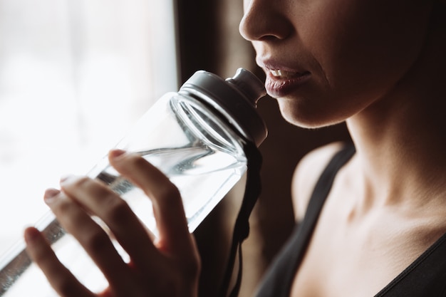 Foto imagen recortada de agua potable de mujer hermosa joven fitness.