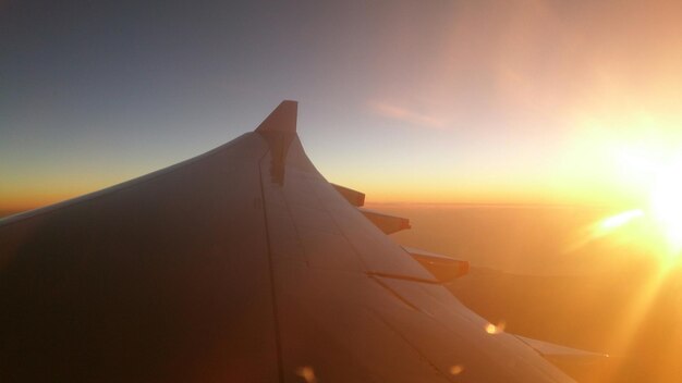 Foto imagen recortada del ala de un avión contra el cielo durante la puesta de sol