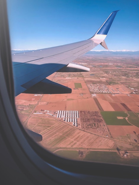 Foto imagen recortada del ala del avión volando sobre el paisaje visto a través de la ventana