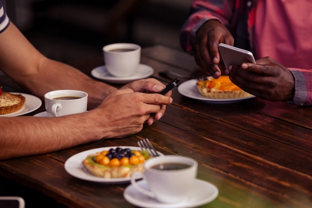 Imagen recortada de amigos comiendo pasteles y tomando café