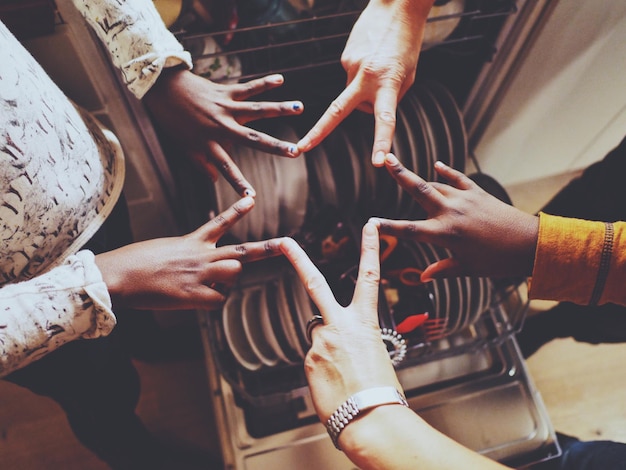 Foto imagen recortada de amigos haciendo forma de estrella sobre el lavador de platos en la cocina