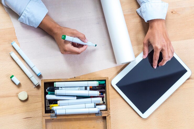 Foto imagen recortada de un artista dibujando en papel mientras usa una tableta digital en la mesa
