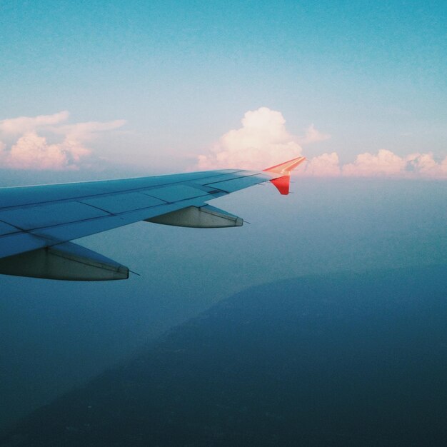 Foto imagen recortada de un avión sobre tierra y mar volando contra el cielo