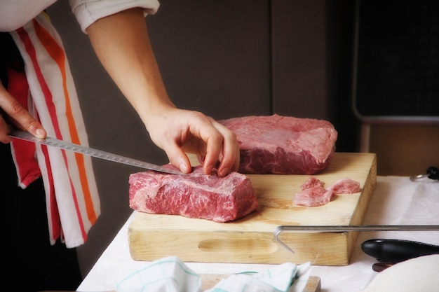 Imagen recortada de un chef cortando carne en la cocina