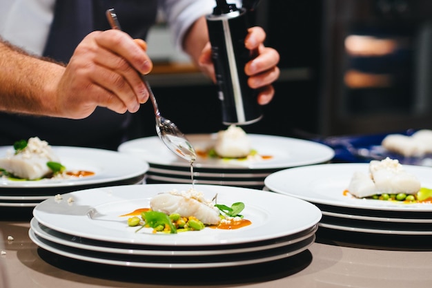 Imagen recortada de un chef preparando mariscos en un plato en un restaurante