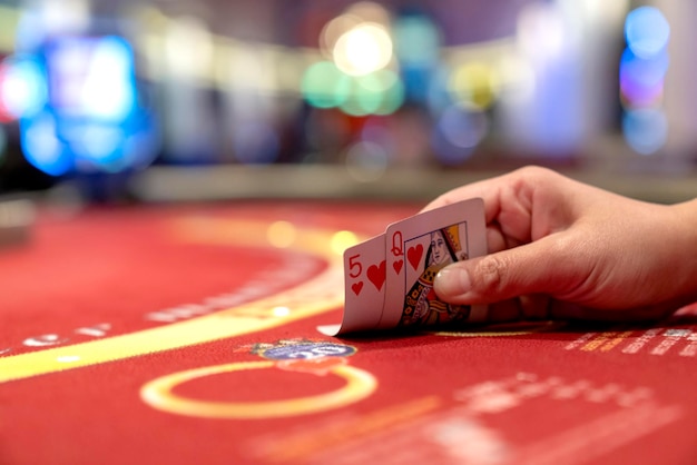 Imagen recortada de una chica jugando al póquer en la mesa del casino y sosteniendo cartas