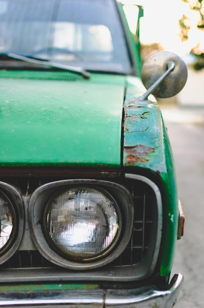 Foto imagen recortada de un coche vintage verde dañado estacionado en la carretera