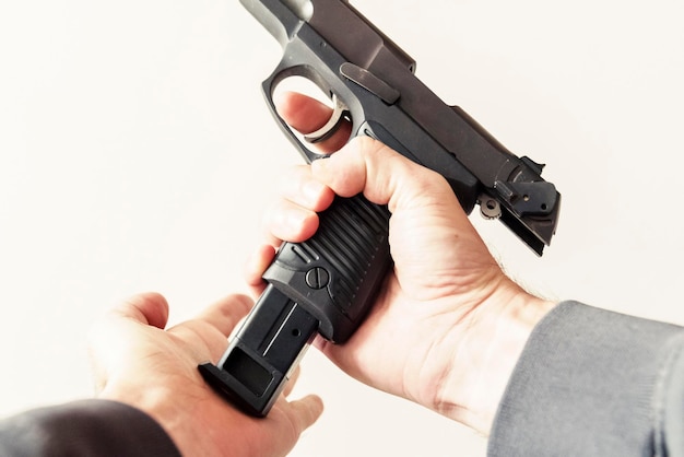 Foto imagen recortada de un criminal cargando un cargador en una pistola contra un fondo blanco
