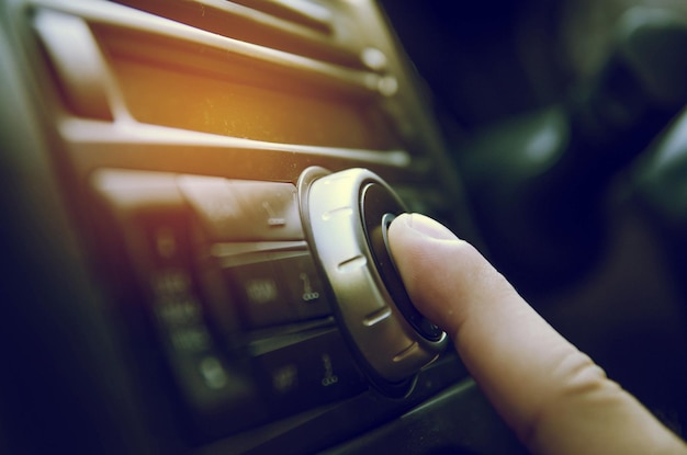 Imagen recortada de un dedo humano tocando el sistema de música en un coche