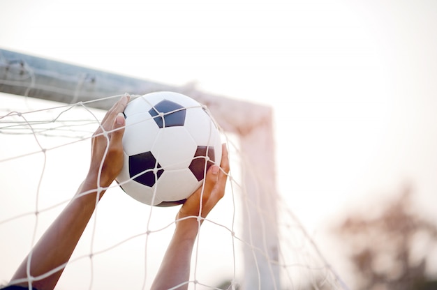 La imagen recortada de los deportistas que atrapan la pelota y el campo de fútbol.